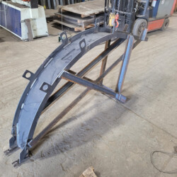 A curved steel structural beam supported by a metal frame in a workshop.