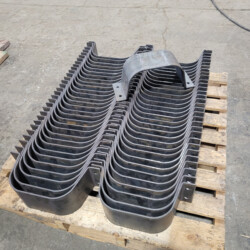Stack of curved metal brackets on a wooden pallet.