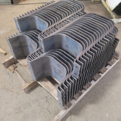 A stack of curved, u-shaped steel brackets on a wooden pallet.