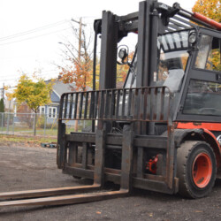 Orange Linde forklift parked on a gravel lot.