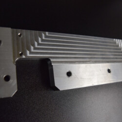A machined metal plate with stepped grooves and pre-drilled holes.