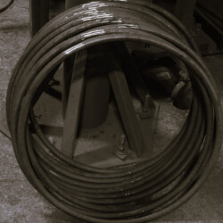 A large coil of thick metal wire or rod stored on a metal stand.