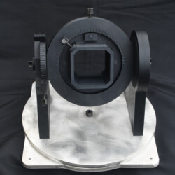 A black, adjustable camera lens hood mounted on a circular, rotating metal base.