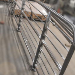 A long, curved metal railing section standing on a shop floor.