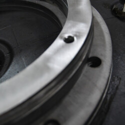 Close-up of a circular, machined metal flange with bolt holes.