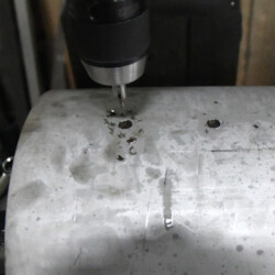 Drill bit drilling into a metal cylinder.