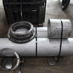 Metal pipes and flange components bundled together on forklift forks.