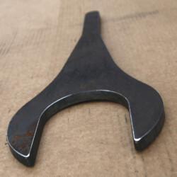 A flat, Y-shaped metal wrench on a brown surface.