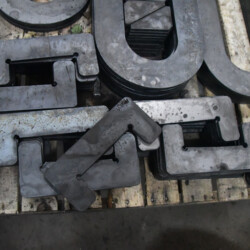 Stacks of various U-shaped and L-shaped metal plates on a wooden pallet.