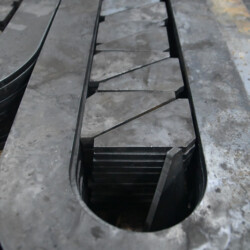 A stack of flat, angular steel pieces nested within an elongated metal frame.