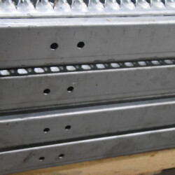 Stacked metal stair treads with perforated edges and bolt holes.